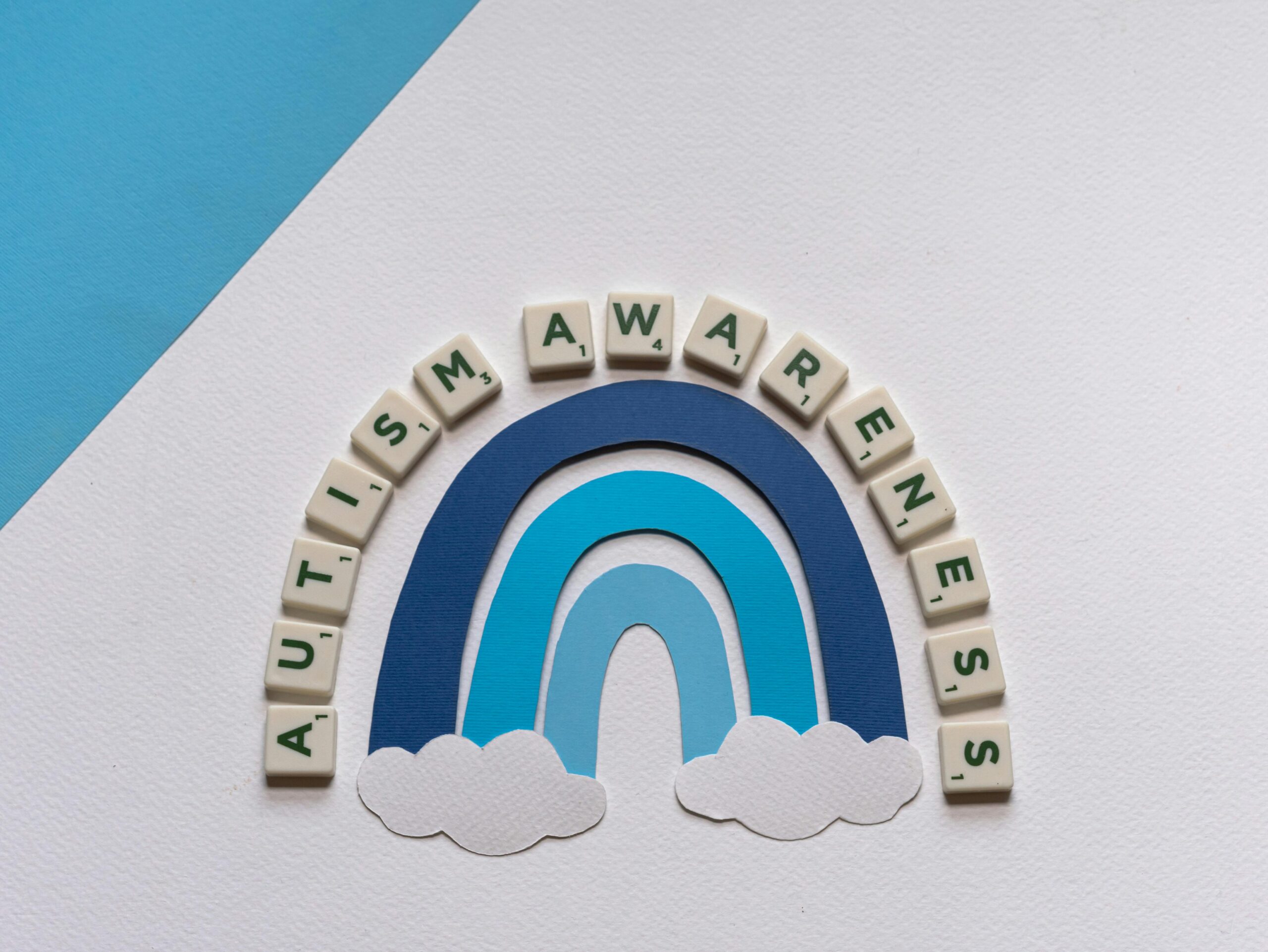 Styled autism awareness design featuring rainbow and letter tiles.