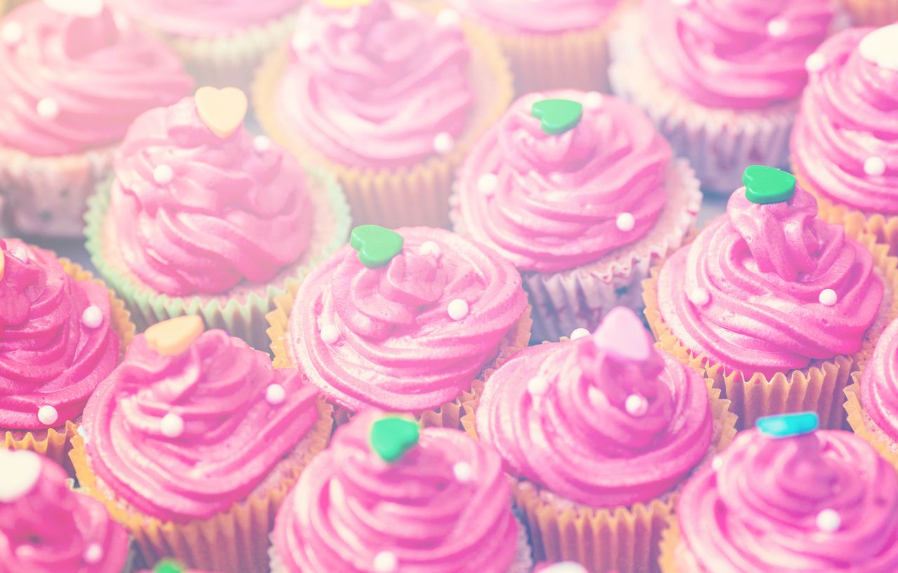 A close-up of pink frosted cupcakes adorned with heart-shaped candies, perfect for any celebration.